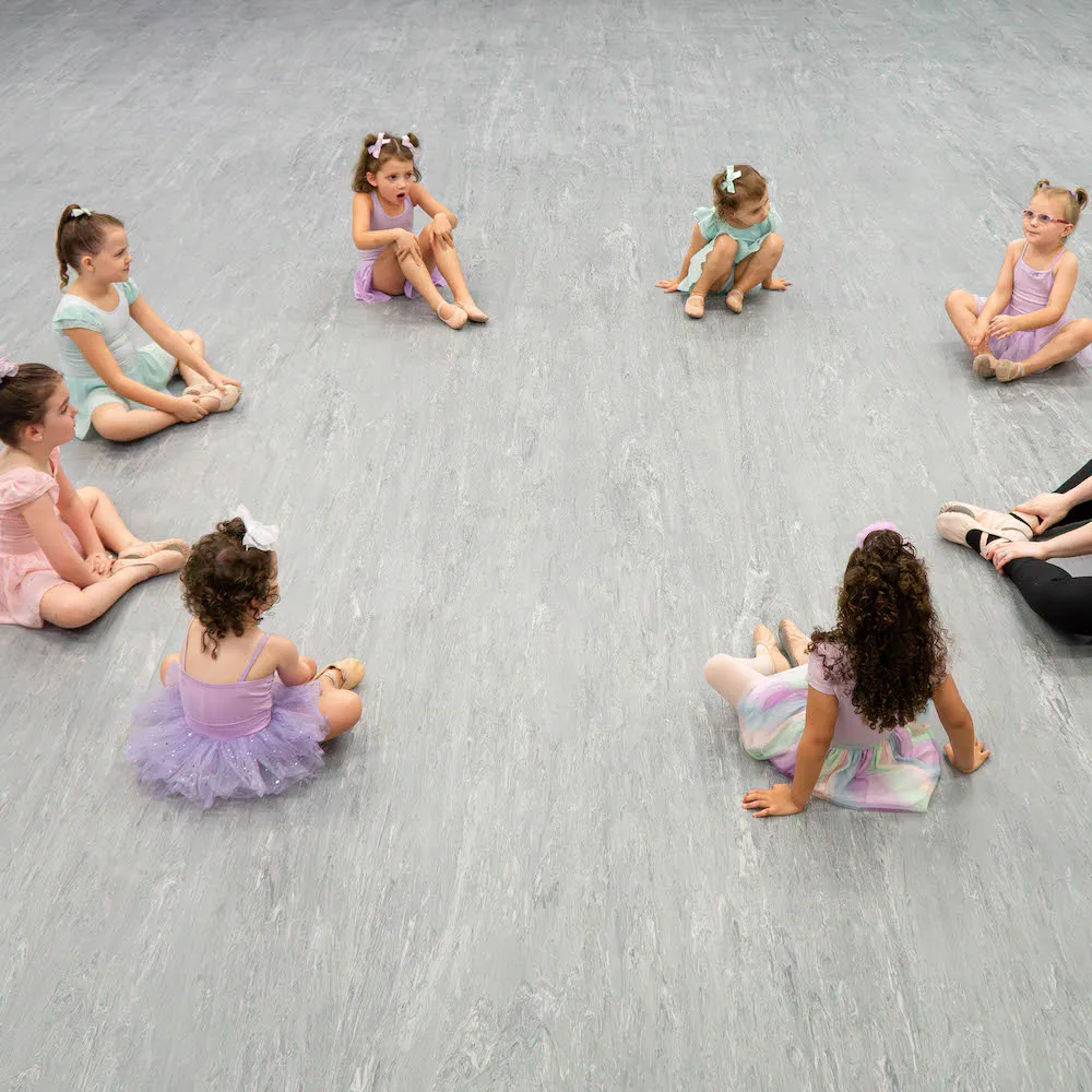 Young dancers sitting in a circle with their teacher.